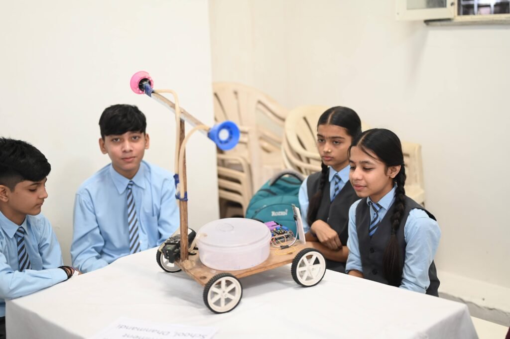 Group of school students presenting a handmade robot at a science exhibition.