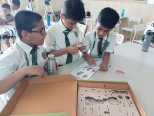 Young students in a Vadodara school STEM Lab collaboratively assembling a DIY science kit while following illustrated instructions.