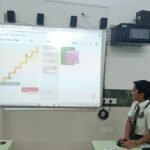 A student solving a Blockly puzzle on a smartboard in a STEM Lab in Delhi Schools.