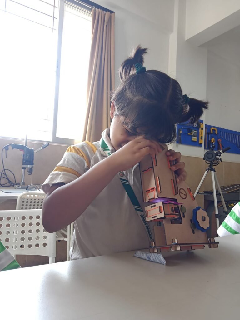Young children working hands-on with mechanical models and telescopic kits in a stem lab in Vadodara schools.