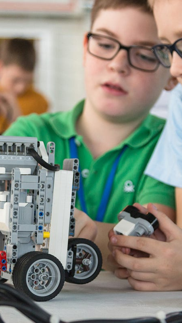 Two boys collaborating on a robotics project in a classroom setting.