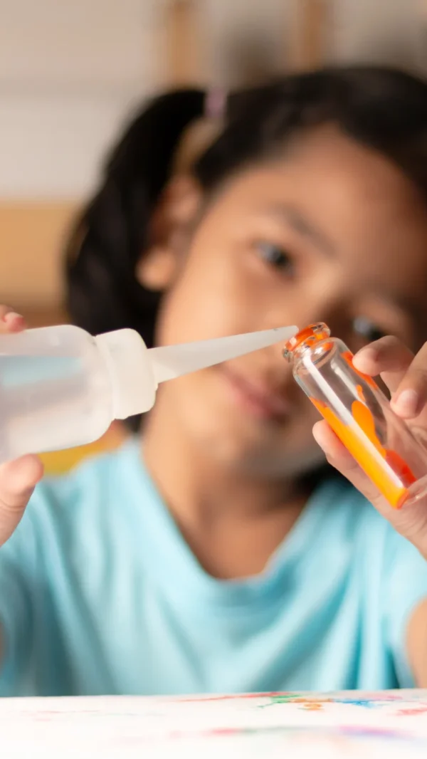 A group of children with their teacher in a school STEM lab in Vadodara, wearing safety goggles and surrounded by lab equipment.